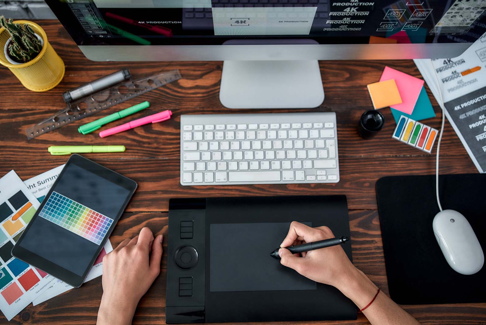 Artist creating a logo with stylist pad on brown desk.